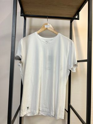 Le t-shirt blanc est suspendu à un portant dans une pièce.