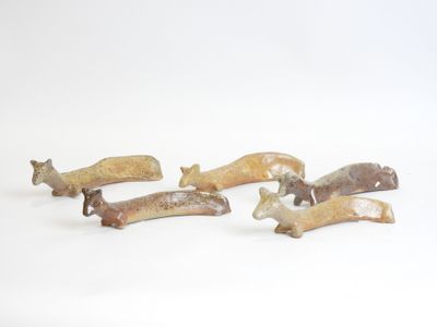 five small figurines of different shapes on a white surface