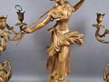 a statue of a woman holding a stick and a candelabra