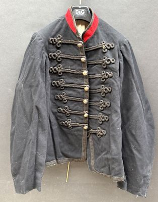 une vieille veste militaire accrochée au mur, avec un col rouge
