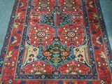 Le tapis posé au sol est rouge et bleu, avec un motif floral.