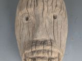 un masque en bois accroché au mur d'une pièce