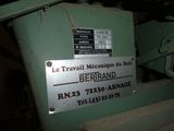 une machine sur laquelle est apposée une pancarte indiquant « Le travail mécanique du bois Bernard »