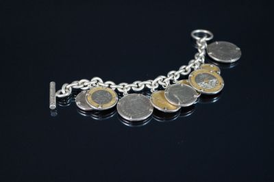 un bracelet en argent orné de pièces de monnaie, posé sur un fond noir