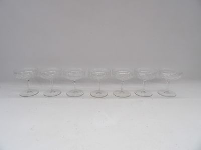 six clear wine glasses lined up in a row on a white surface