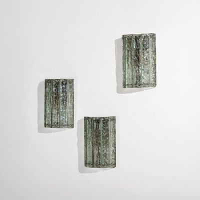 trois morceaux de verre vert sur un mur blanc, avec un fond blanc