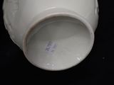 a close up of a white vase on a black surface