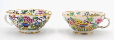 two cups with flowers and birds painted on them on a white surface