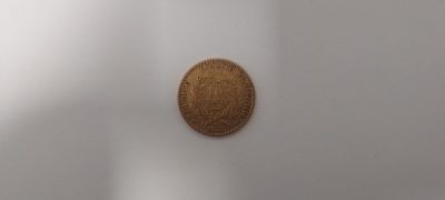 une pièce de monnaie marron posée sur une surface blanche dans une pièce
