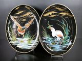 two plates with birds painted on them sitting on a table