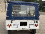 a small white vehicle with a blue cover parked in a parking lot