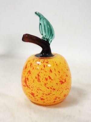 une pomme en verre surmontée d'une feuille verte