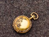 une image représentant une montre de poche en or ornée de perles