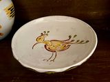 une assiette sur laquelle est peint un oiseau, à côté d'un vase