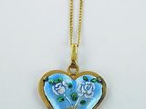 a close up of a heart shaped necklace with flowers on it