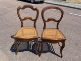 two wooden chairs sitting on the side of the road