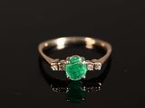 une bague en émeraude et diamant sur une surface noire
