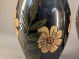 two vases with flowers painted on them sitting on a table