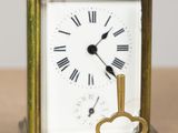une petite horloge en laiton avec une clé, posée sur une table