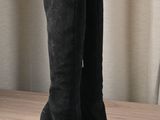 tall black boots on a wooden table with curtains in the background