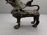 une vieille statue en bronze représentant un lion avec un oiseau sur le dos