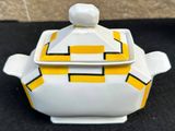 a yellow and white bowl with a lid on a black surface