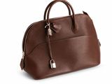 Le sac à main en cuir marron est posé sur une surface blanche.