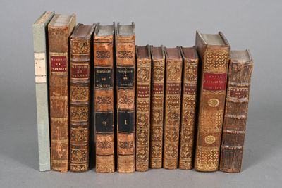several old books are lined up in a row on a gray surface