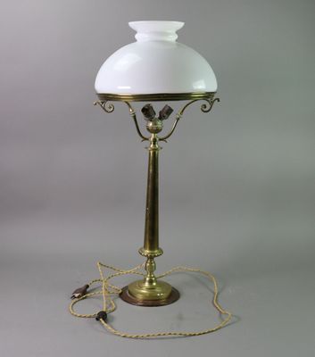 an antique brass table lamp with a white glass shade and a gold chain