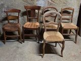 quatre chaises en bois placées les unes à côté des autres devant un mur en pierre