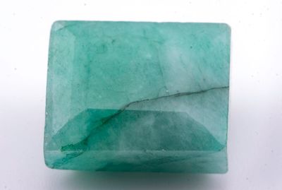un gros plan d'une pierre verte sur une surface blanche
