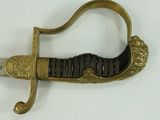 a gold colored sword with a black handle on a white surface