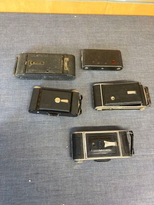 five old cell phones sitting on a blue surface