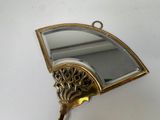 a gold fan shaped mirror hanging on a wall