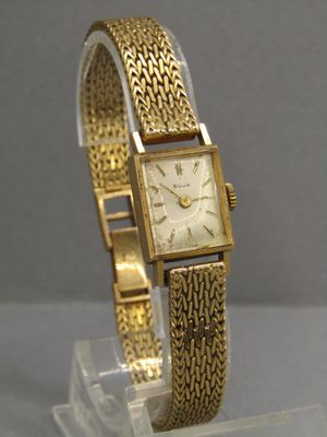 an image of a gold wrist watch on a clear display stand