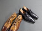 two pairs of brown and black shoes sitting on top of a table