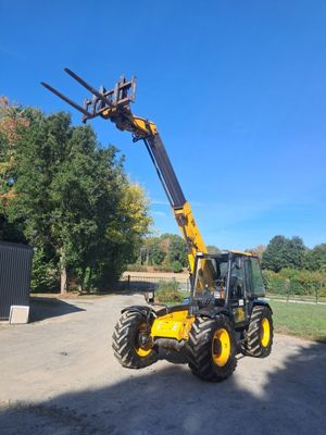 un tracteur équipé d'une fourche est garé sur un chemin de terre