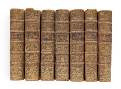six old books lined up in rows on a white surface