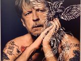 une image représentant un homme tatoué tenant un oiseau