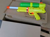 a yellow and green toy gun on top of a cardboard box