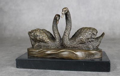 sculpture en bronze représentant deux cygnes sur un lac, avec de l'eau au premier plan