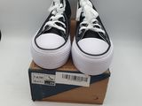 des baskets Converse noires et blanches avec des lacets blancs, posées sur une boîte en carton