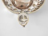an antique silver cup and saucer on a white table