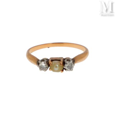 un gros plan d'une bague en or sertie de deux diamants et d'une perle