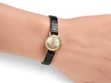 wrist shot of a woman wearing a gold watch with a black band