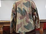 a camouflage jacket on a wooden stand next to a table