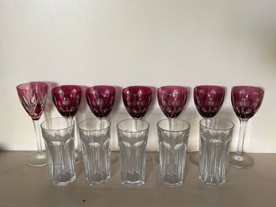 six wine glasses are lined up on a shelf next to a lamp