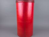 an old red tin canister with a lid on a gray background