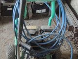 une machine verte à laquelle est raccordé un tuyau, dans un garage