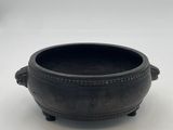 a black bowl with handles and handles on a white surface